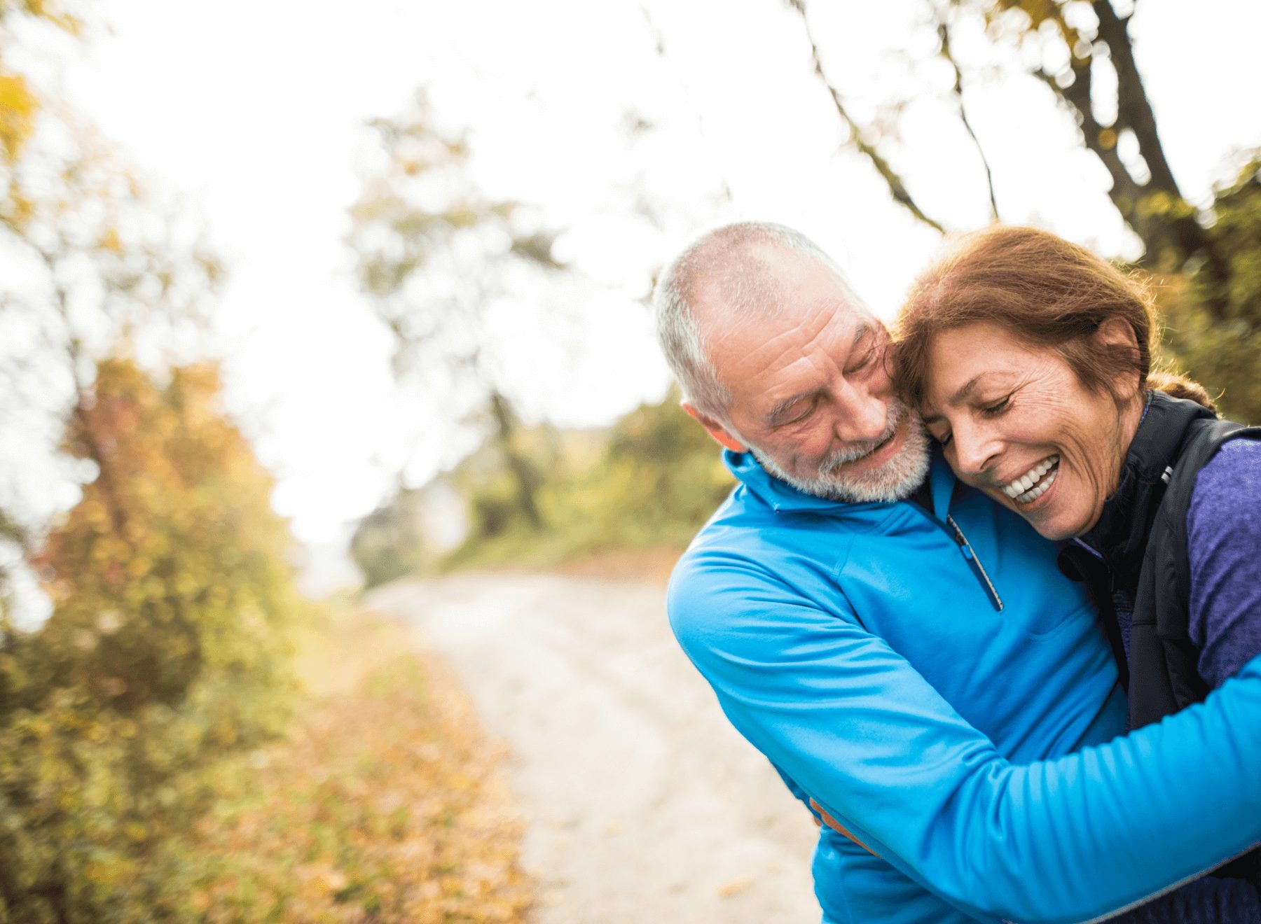 Senior couple hugging one another on a wooded path