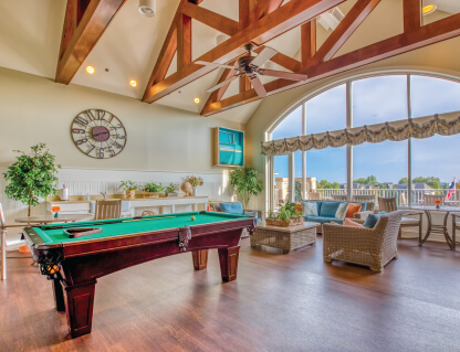 Spacious recreational room with a pool table, large windows, and comfortable seating area.