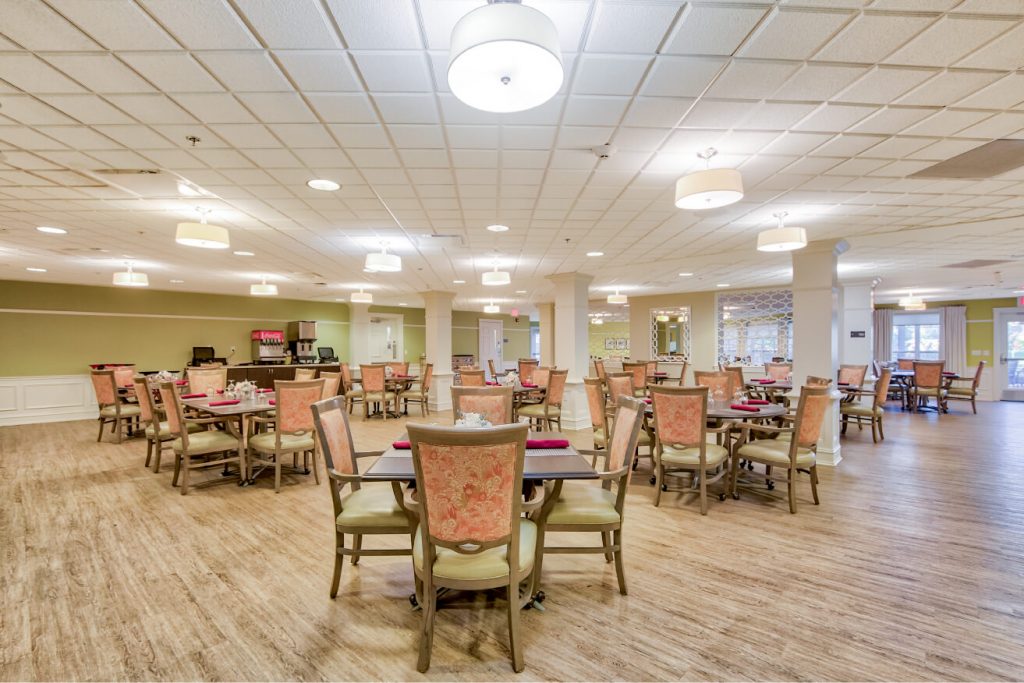 Spacious dining area with multiple tables and chairs, wooden flooring, and ceiling lights.