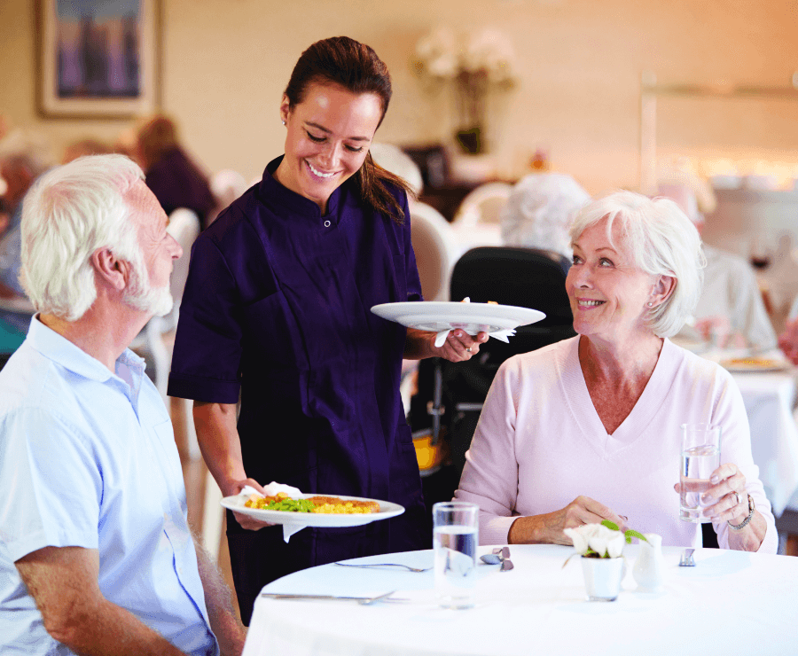 staff member serving food to senior couple